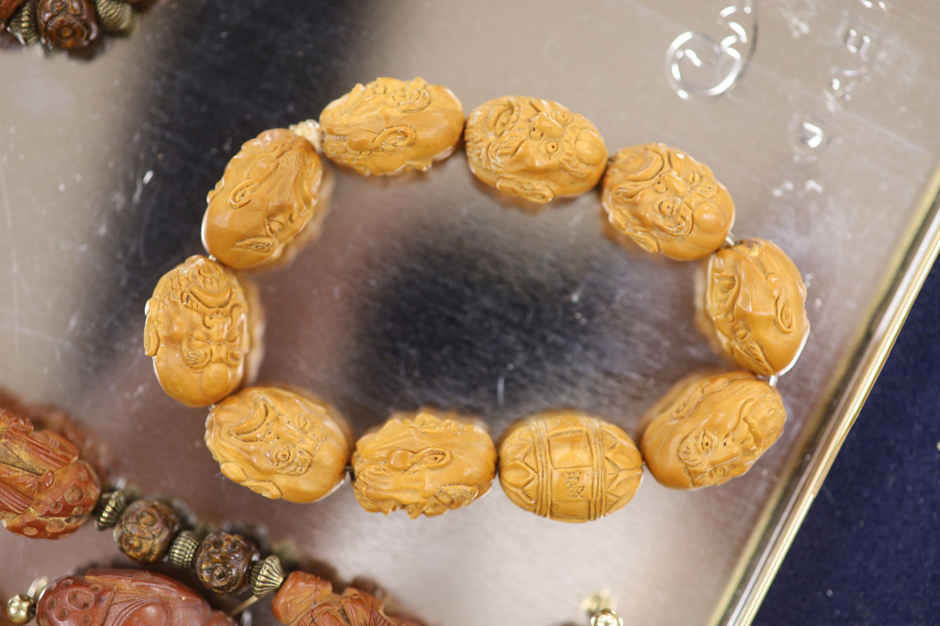 A Chinese peach stone or nut bead necklace, bracelet, a pair of earrings and two carved beads